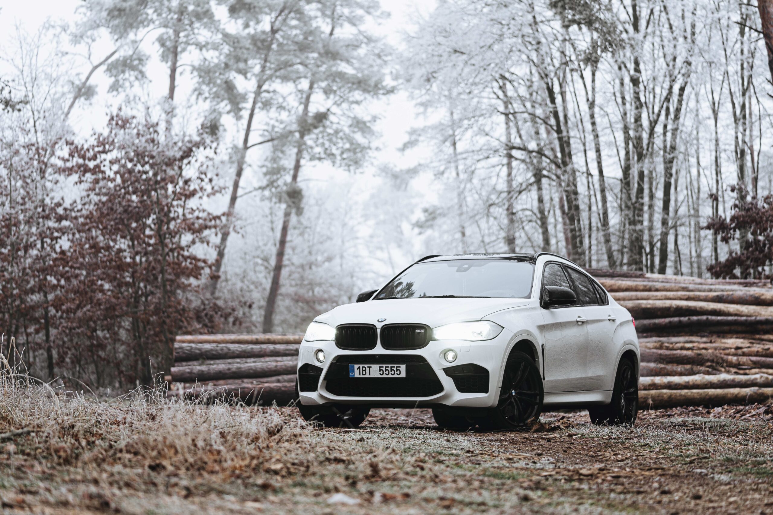 A white BMW SUV with all-season tires parked in a wintry location.